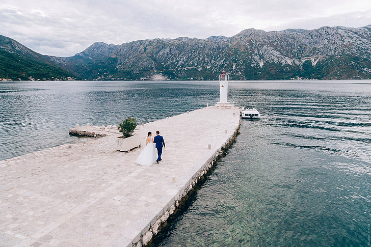 bride and groom walking on dock during daytime