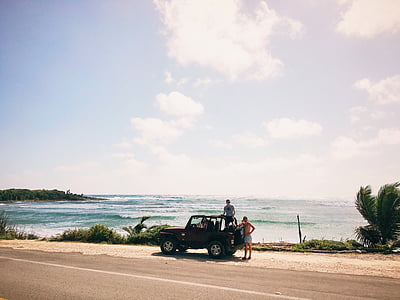 two men near beach standing beside Jeep Wrangler