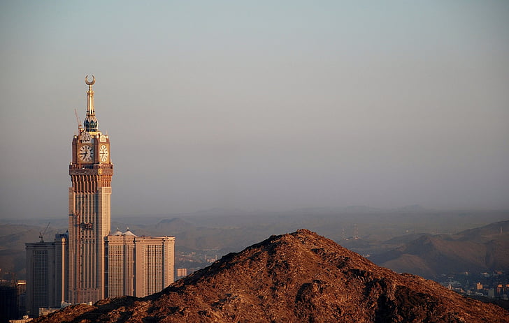 brown and gold tower clock surrounded with mountains