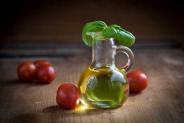 glass jug filled with oil with tomatoes on the table