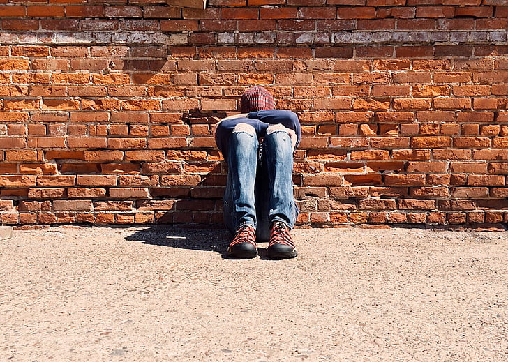 man laying on brick wall