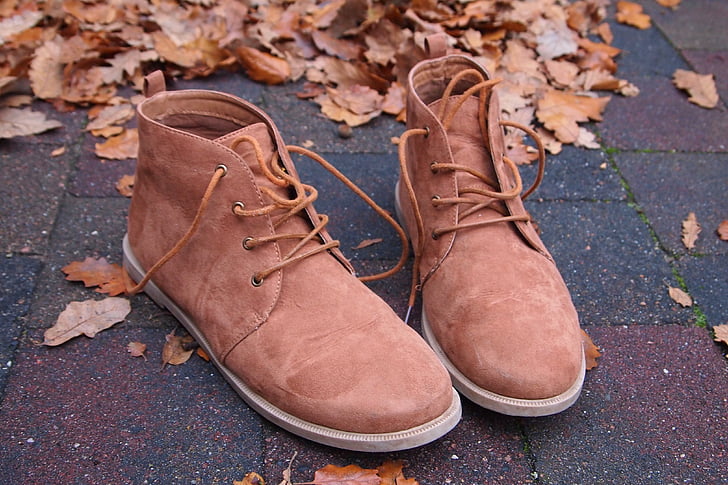 pair of brown suede high-top sneakers on gray concrete pavement