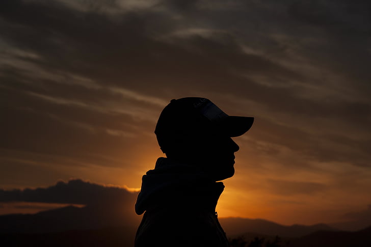 silhouette photo of person wearing cap