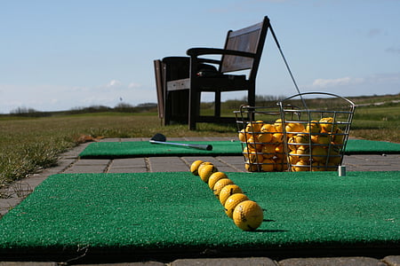yellow golf balls near black wooden bench