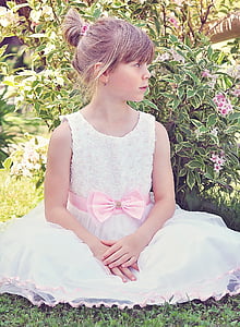 girl in white sleeveless gown sitting beside the flowers