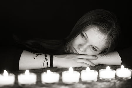grayscale photo of woman laying looking tealight candles