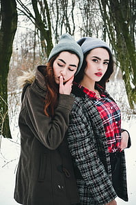 two woman wearing knit caps and coats under snowfield