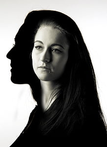 grayscale photo of woman with her shadow