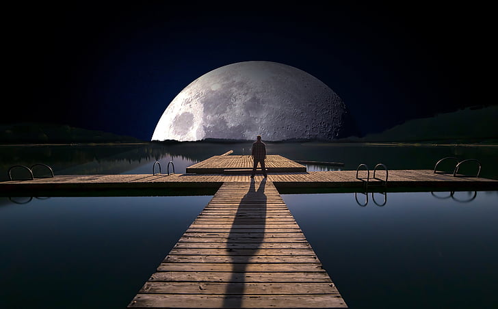 man standing on wooden dock at night