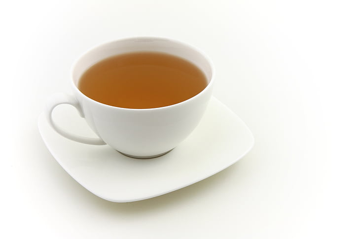 filled white ceramic teacup against white background