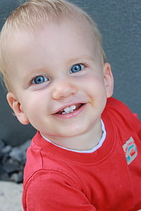 boy smiling while wearing red crew-neck t-shirt