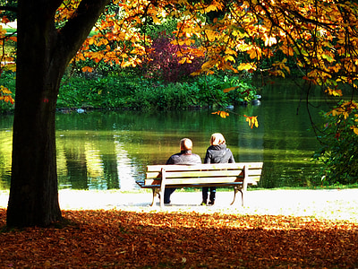 two people sitting on brown outdoor bench