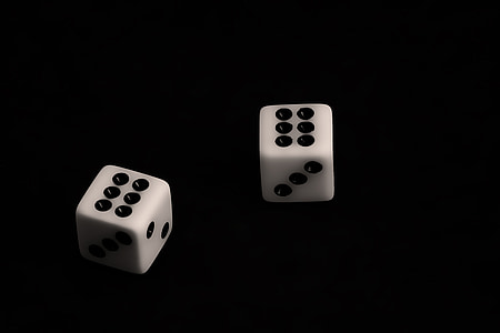 two white-and-black dice on black surface