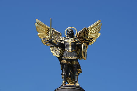 man with wings holding sword statue under blue skies at daytime