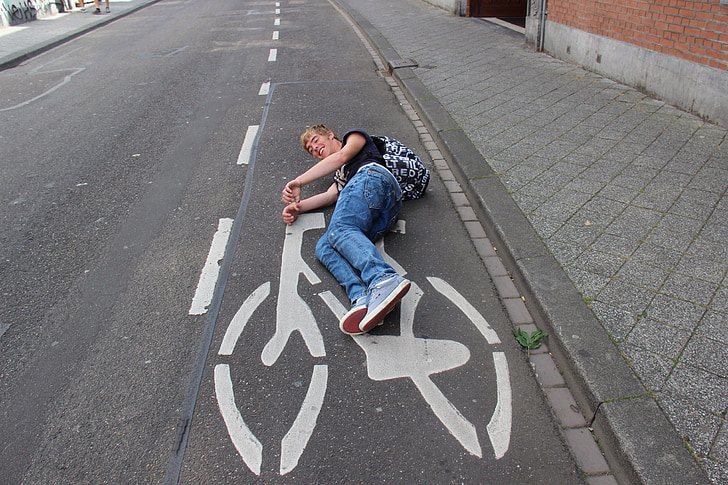 man laying on concrete road