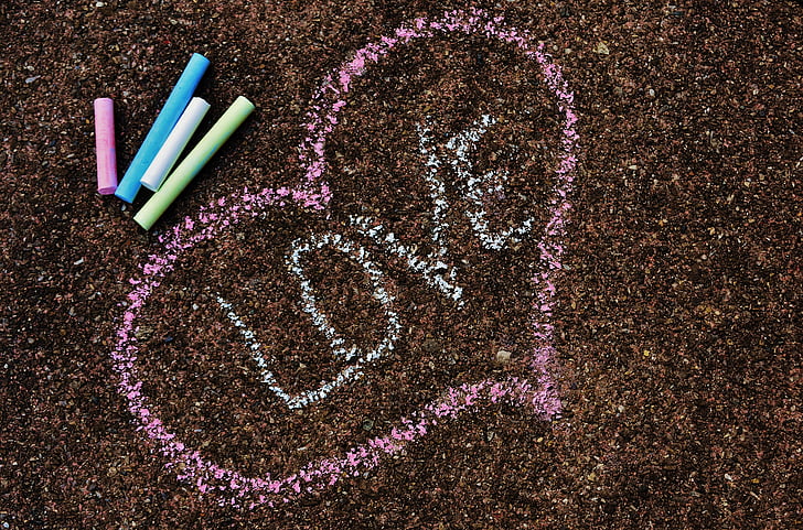 love text inside pink heart beside assorted-color chalks