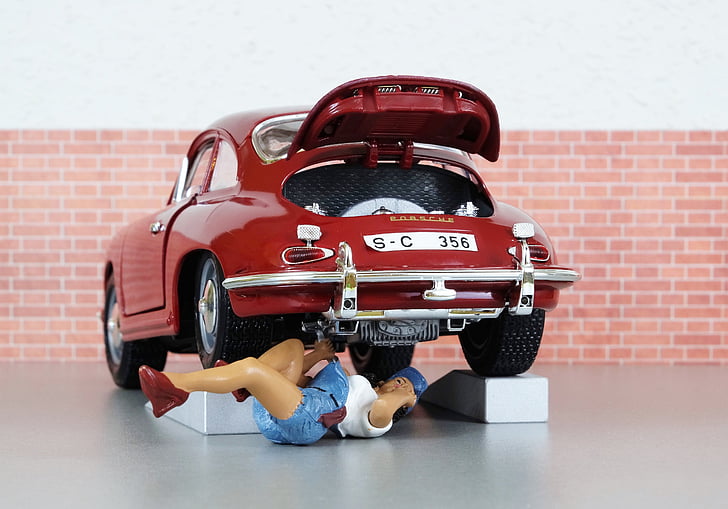 person lying under car while repairing scale model