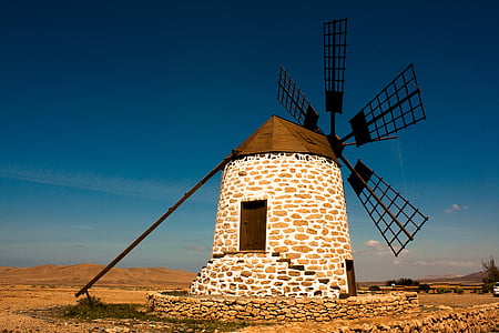 photo of white and brown concrete windmill under blue sky at daytime