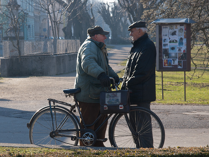 two men talking in front of bicycle on street