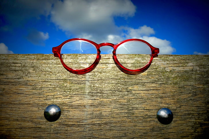 red framed eyeglasses on brown wooden frame