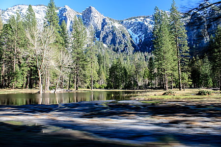 calm body of water near trees and mountain