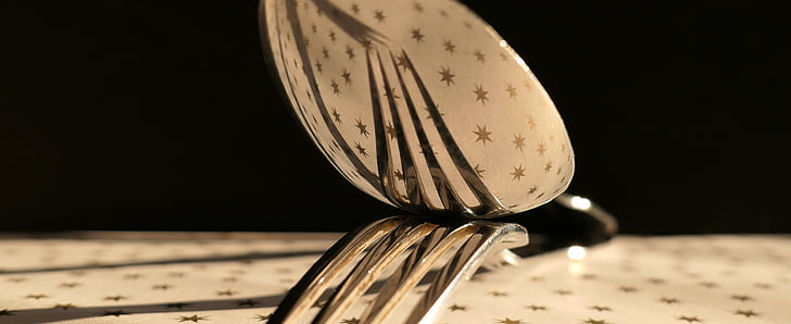 stainless steel spoon top of fork on table