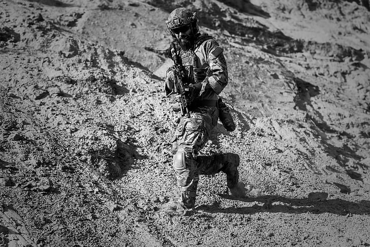 soldier carrying rifle walking on sand