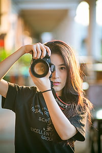 woman wearing shirt while holding canon dslr camera