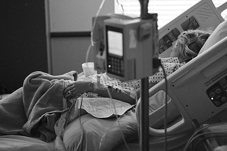 greyscale photo of person lying on hospital bed