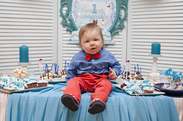 child in blue dress shirt and red pants