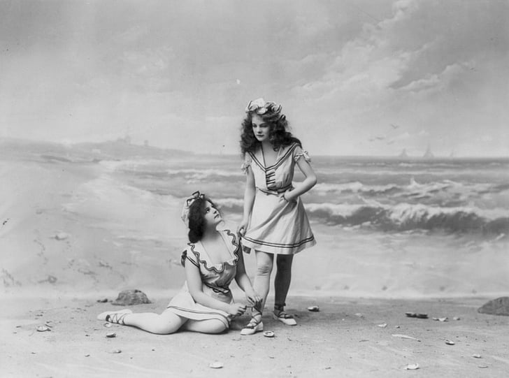 two women wearing dresses near seashore painting