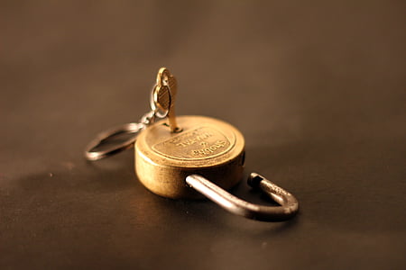 gold-colored padlock with grey metal key