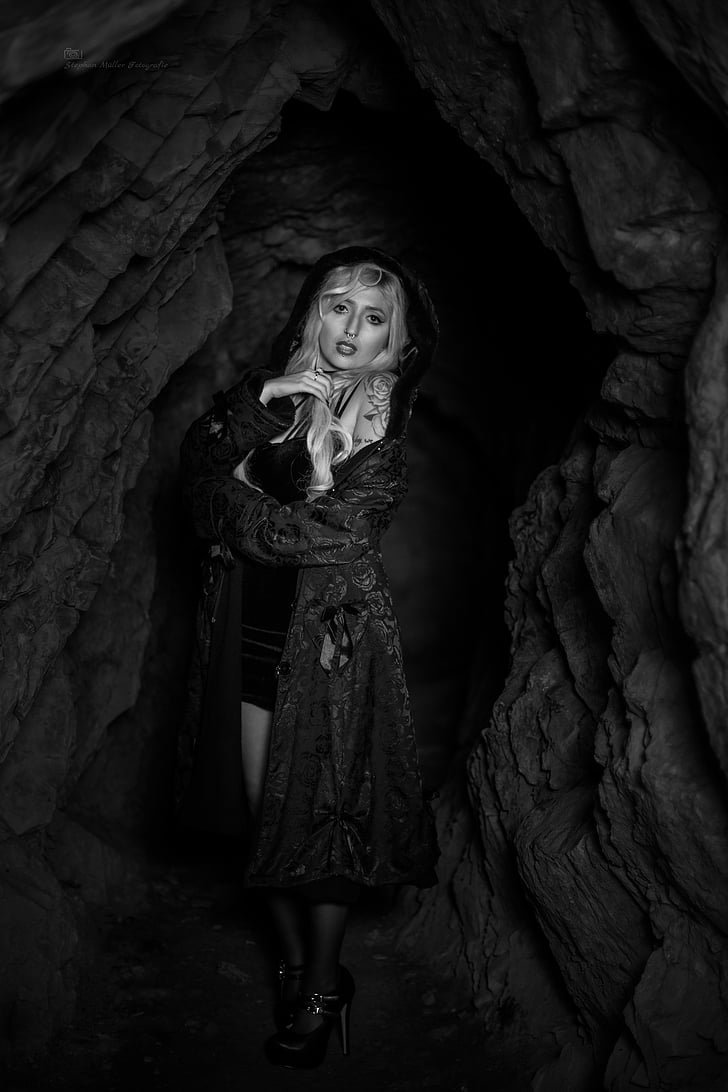 grayscale photography of woman wearing robe inside cave