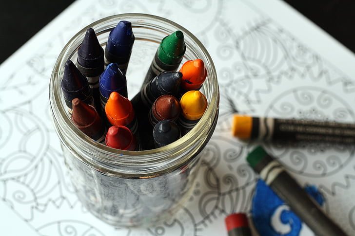 assorted-color crayons in clear glass jar