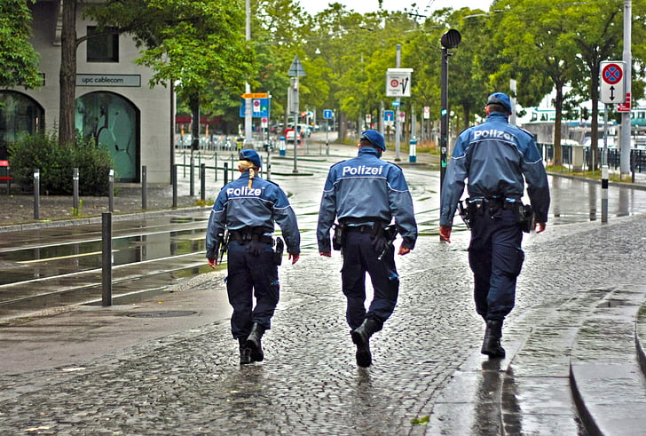 three Police officers walking on black road