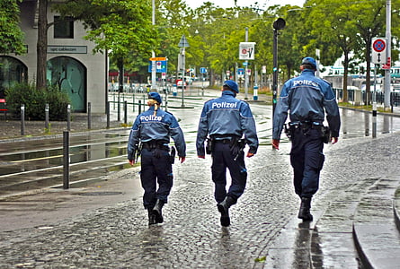 three Police officers walking on black road