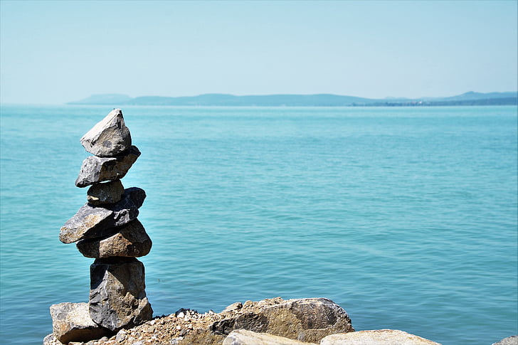 balanced of gray stone near body of water