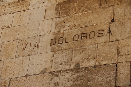 closeup photo of gray concrete wall with VIA Dolorosa carved