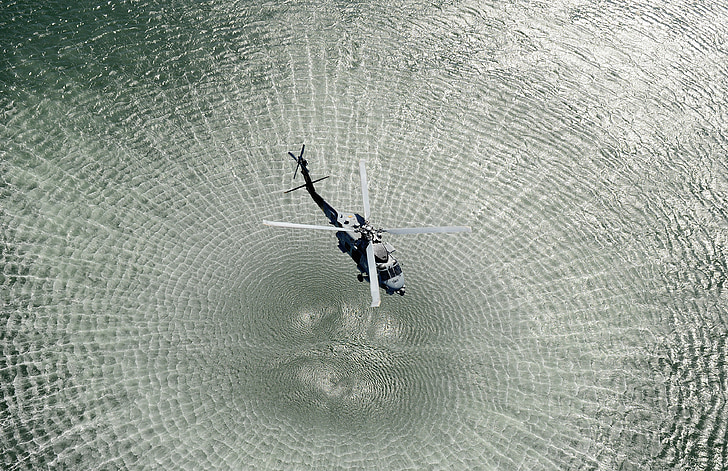 black helicopter forming water ripple