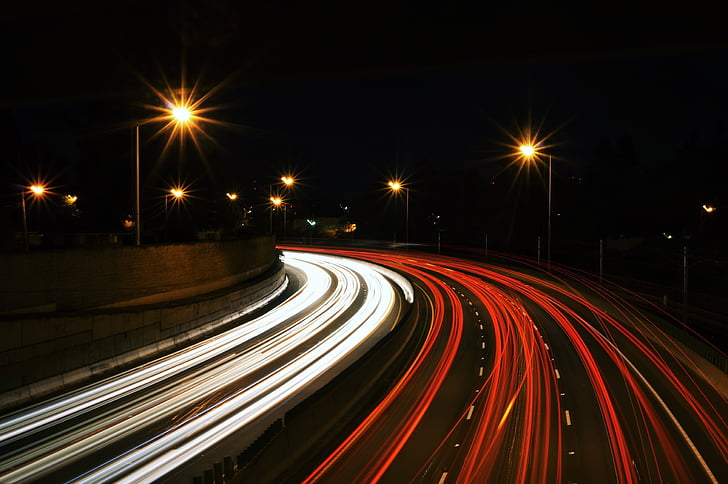 time lapse photo of road with running vehicles during night time