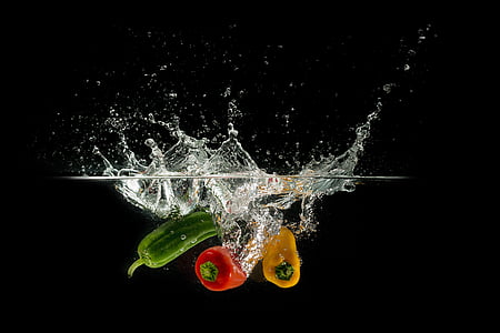 photo of three assorted-color bell peppers dropped in body of water