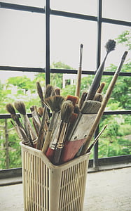 assorted-color paintbrush inside white plastic basket