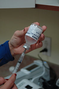 person holding syringe and vial