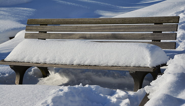 snow on brown wooden bench