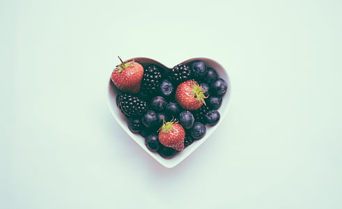strawberry, blueberry, and blackberry in heart shape bowl