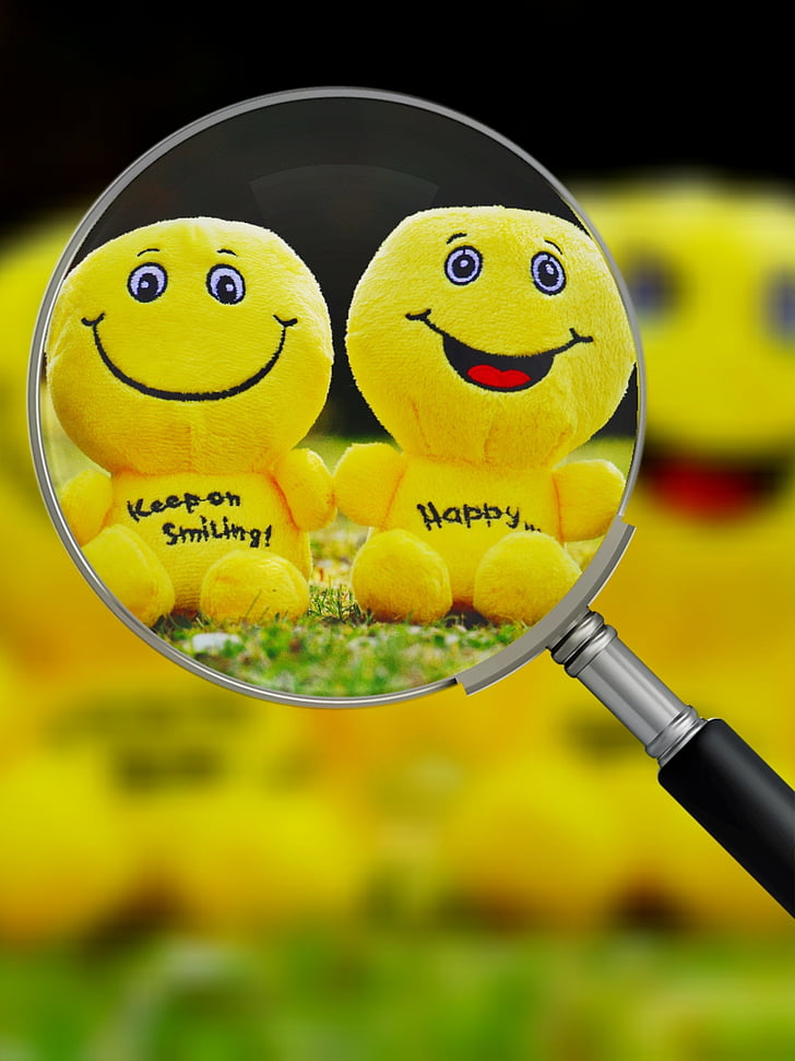 two yellow emoji plush toys in magnifying glass