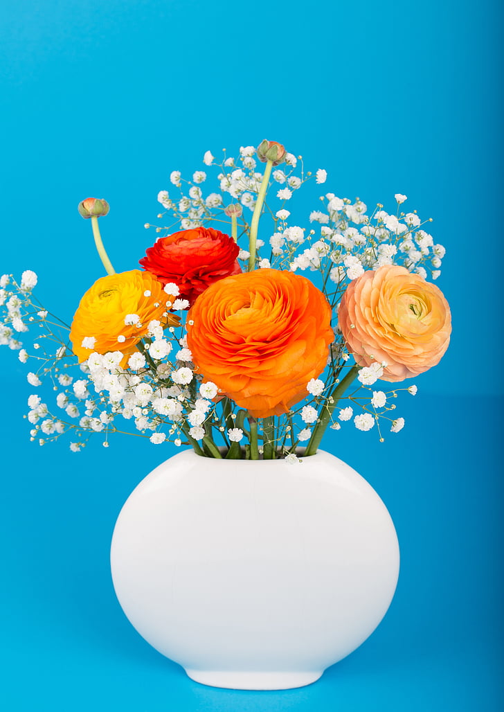 orange, yellow, and red petaled flowers in white ceramic vase