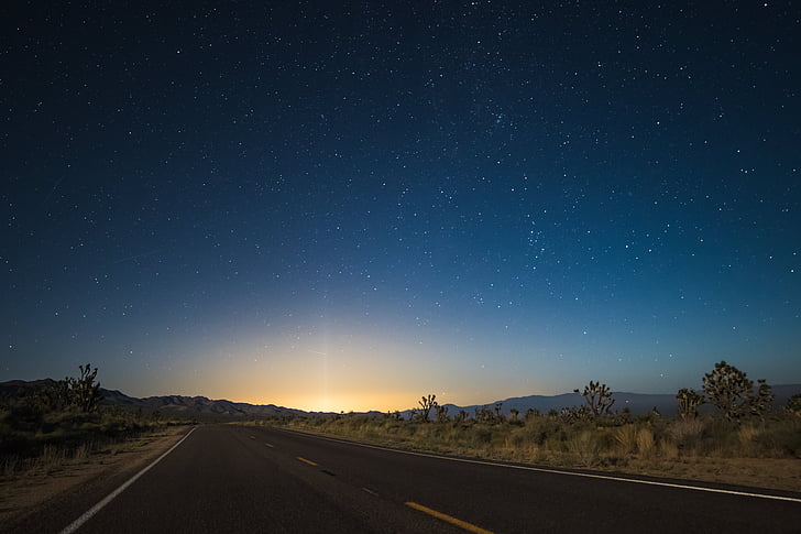 time laps photo of star night sky to sunrise on asphalt road