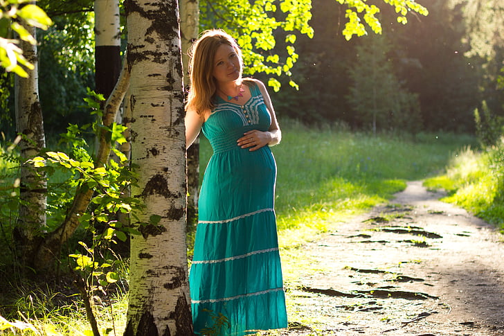 woman green sleeveless dress standing beside tree