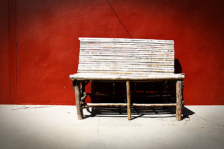 brown wooden bench near red wall paint